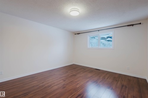 Empty room with dark wood-type flooring and a textured ceiling - 243 Rhatigan Road E, Edmonton, AB - Indoor Photo Showing Other Room