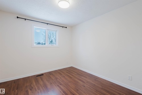 Unfurnished room featuring dark wood-style flooring and a textured ceiling - 243 Rhatigan Road E, Edmonton, AB - Indoor Photo Showing Other Room