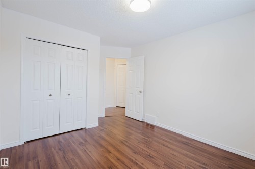 Unfurnished bedroom featuring a closet, dark wood finished floors, and a textured ceiling - 243 Rhatigan Road E, Edmonton, AB - Indoor Photo Showing Other Room