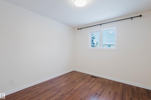Empty room with a textured ceiling and dark wood finished floors - 243 Rhatigan Road E, Edmonton, AB - Indoor Photo Showing Other Room
