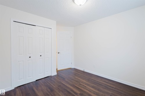 Unfurnished bedroom with dark wood finished floors, a textured ceiling, and a closet - 243 Rhatigan Road E, Edmonton, AB - Indoor Photo Showing Other Room