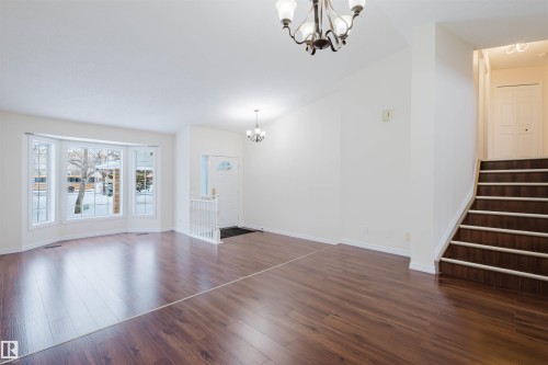 Unfurnished living room with hanging lights, dark wood-style flooring, and lofted ceiling - 243 Rhatigan Road E, Edmonton, AB - Indoor Photo Showing Other Room