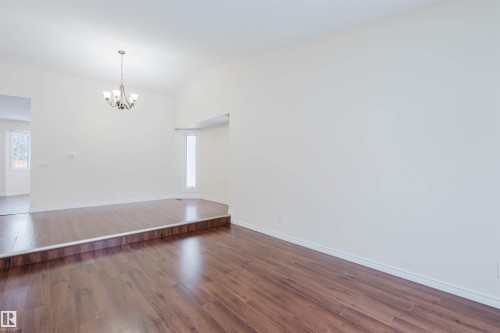 Unfurnished room featuring vaulted ceiling, dark wood-style floors, and hanging lights - 243 Rhatigan Road E, Edmonton, AB - Indoor Photo Showing Other Room