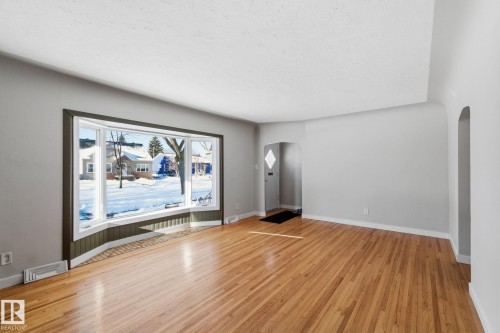 Unfurnished living room with arched walkways and light wood-style flooring - 12225 134 Street, Edmonton, AB - Indoor Photo Showing Other Room