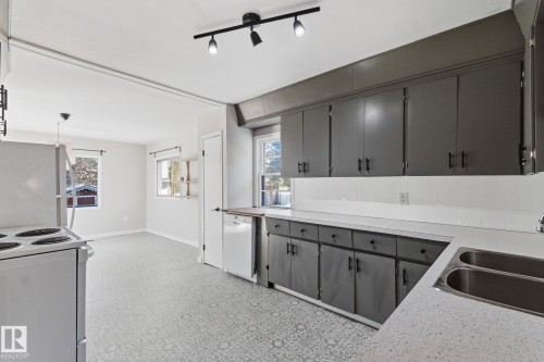 Kitchen featuring gray cabinets, white appliances, light countertops, decorative backsplash, and rail lighting - 12225 134 Street, Edmonton, AB - Indoor Photo Showing Kitchen With Double Sink