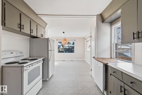 Kitchen with white appliances, gray cabinets, hanging light fixtures, light flooring, and decorative backsplash - 12225 134 Street, Edmonton, AB - Indoor Photo Showing Kitchen