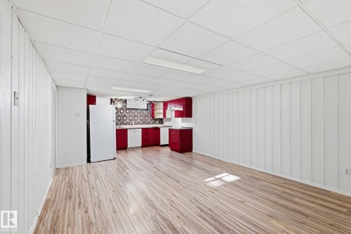 Bar area featuring wood walls, white appliances, light wood-style floors, a paneled ceiling, and tasteful backsplash - 12225 134 Street, Edmonton, AB - Indoor Photo Showing Other Room