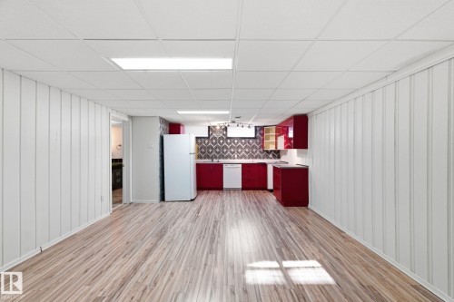 Kitchen featuring white appliances, wooden walls, backsplash, light wood-type flooring, and a paneled ceiling - 12225 134 Street, Edmonton, AB - Indoor Photo Showing Other Room