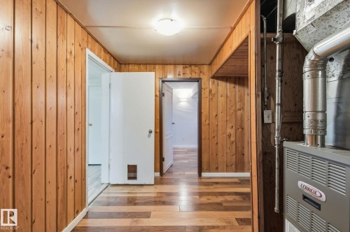 Hallway featuring wooden walls, light wood-type flooring, and heating unit - 12225 134 Street, Edmonton, AB - Indoor Photo Showing Other Room