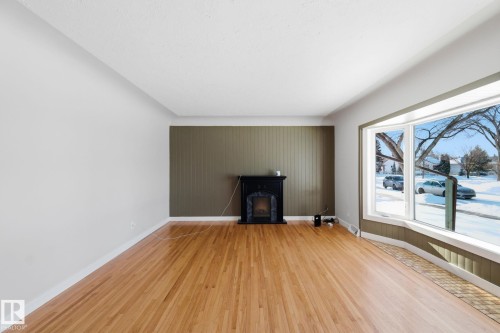 Unfurnished living room with light wood-style floors and baseboards - 12225 134 Street, Edmonton, AB - Indoor With Fireplace