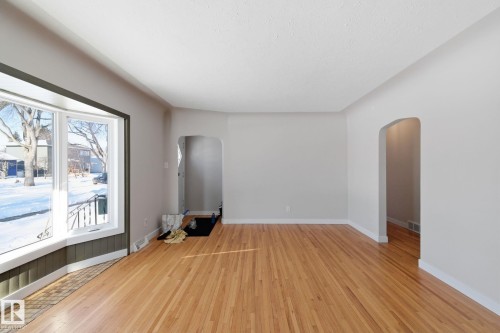 Empty room featuring arched walkways and light wood-style flooring - 12225 134 Street, Edmonton, AB - Indoor Photo Showing Other Room