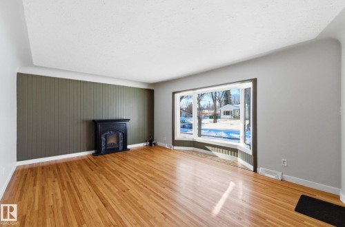 Unfurnished living room with light wood-type flooring and a fireplace - 12225 134 Street, Edmonton, AB - Indoor Photo Showing Living Room With Fireplace
