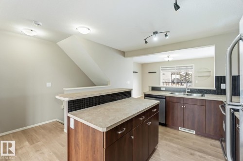 Kitchen with light countertops, light wood-type flooring, and stainless steel appliances - 16 3751 12 Street, Edmonton, AB - Indoor Photo Showing Kitchen