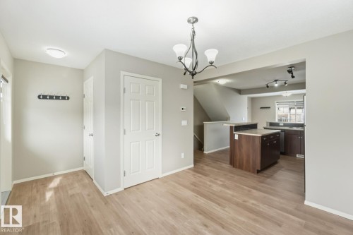 Kitchen with light countertops, suspended lighting, a center island, and light wood finished floors - 16 3751 12 Street, Edmonton, AB - Indoor