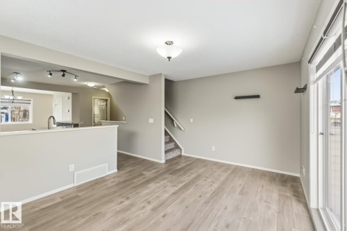 Unfurnished living room with healthy amount of natural light, light wood-type flooring, and a chandelier - 16 3751 12 Street, Edmonton, AB - Indoor Photo Showing Other Room