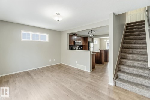 Unfurnished living room featuring light wood-style flooring and hanging lights - 16 3751 12 Street, Edmonton, AB - Indoor Photo Showing Other Room