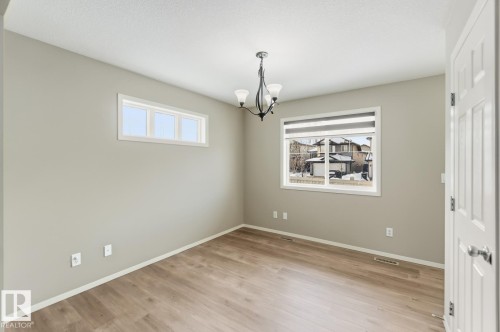 Unfurnished room with hanging lights and light wood-style floors - 16 3751 12 Street, Edmonton, AB - Indoor Photo Showing Other Room