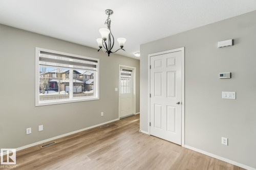 Unfurnished dining area with hanging lights and light wood-style flooring - 16 3751 12 Street, Edmonton, AB - Indoor Photo Showing Other Room