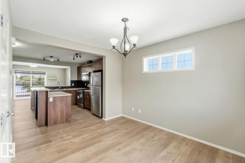 Kitchen featuring light countertops, hanging lights, stainless steel appliances, light wood finished floors, and a kitchen bar - 16 3751 12 Street, Edmonton, AB - Indoor