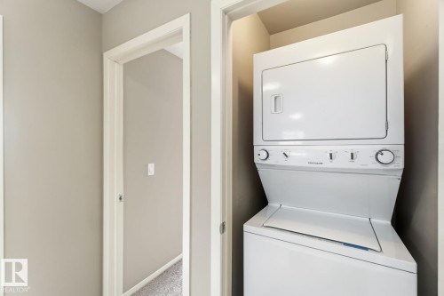 Laundry room with stacked washer and clothes dryer and light colored carpet - 16 3751 12 Street, Edmonton, AB - Indoor Photo Showing Laundry Room