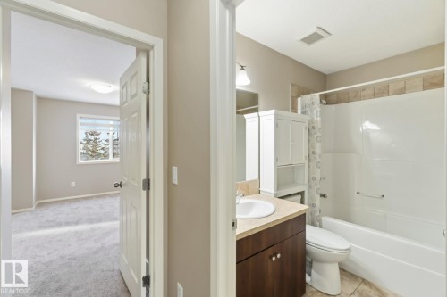 Full bath featuring vanity, shower / tub combo with curtain, and light colored carpet - 16 3751 12 Street, Edmonton, AB - Indoor Photo Showing Bathroom