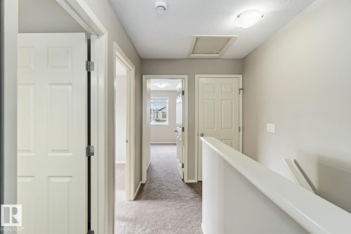 Hallway with light carpet, an upstairs landing, and a textured ceiling - 16 3751 12 Street, Edmonton, AB - Indoor Photo Showing Other Room