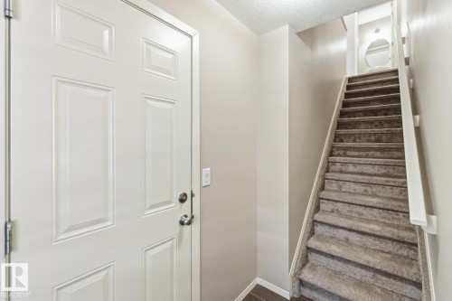 Staircase with a textured ceiling and wood finished floors - 16 3751 12 Street, Edmonton, AB - Indoor Photo Showing Other Room