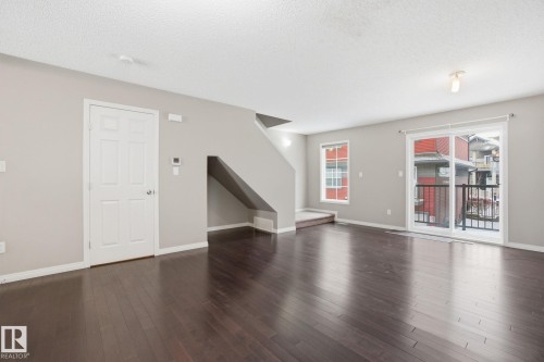 Unfurnished living room with dark wood-type flooring and a textured ceiling - 71 4029 Orchards Drive, Edmonton, AB - Indoor