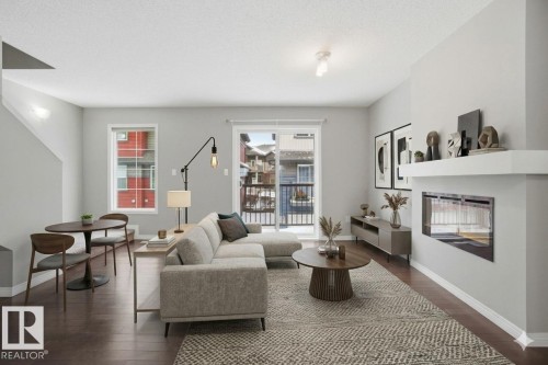 Living room with dark wood finished floors and a glass covered fireplace - 71 4029 Orchards Drive, Edmonton, AB - Indoor Photo Showing Living Room