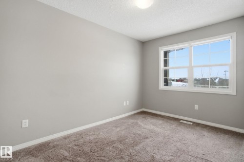 Empty room with light colored carpet and a textured ceiling - 71 4029 Orchards Drive, Edmonton, AB - Indoor Photo Showing Other Room
