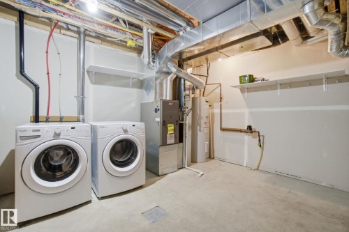 Laundry area with unfinished concrete flooring, electric water heater, independent washer and dryer, and heating unit - 71 4029 Orchards Drive, Edmonton, AB - Indoor Photo Showing Laundry Room