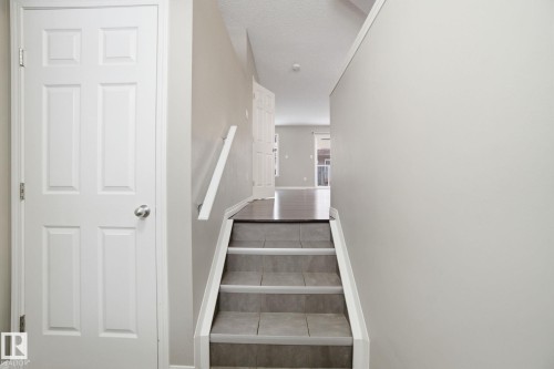 Stairway featuring a textured ceiling and tile patterned floors - 71 4029 Orchards Drive, Edmonton, AB - Indoor Photo Showing Other Room