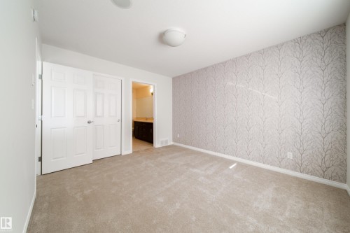 Unfurnished bedroom with wallpapered walls, a closet, ensuite bathroom, and light colored carpet - 1199 Watt Drive, Edmonton, AB - Indoor Photo Showing Other Room