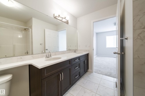 Full bathroom with double vanity, light marble finish flooring, a shower, and light colored carpet - 1199 Watt Drive, Edmonton, AB - Indoor Photo Showing Bathroom