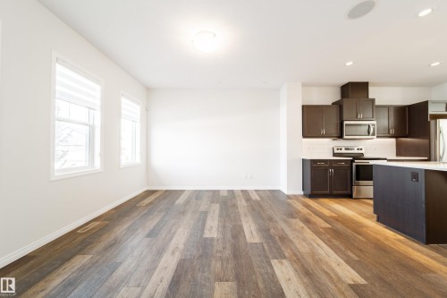 Kitchen with dark wood finish cabinets, dark wood finished floors, stainless steel appliances, tasteful backsplash, and recessed lighting - 1199 Watt Drive, Edmonton, AB - Indoor Photo Showing Kitchen