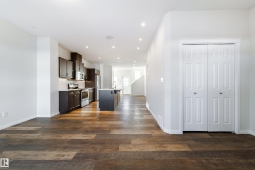 Kitchen with a center island with sink, stainless steel appliances, open floor plan, light countertops, and dark wood finish cabinets - 1199 Watt Drive, Edmonton, AB - Indoor