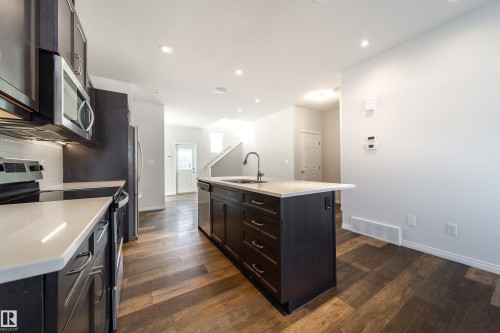 Kitchen featuring stainless steel appliances, an island with sink, dark wood-type flooring, recessed lighting, and dark wood finish cabinets - 1199 Watt Drive, Edmonton, AB - Indoor Photo Showing Kitchen With Upgraded Kitchen