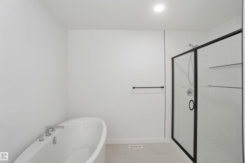 Full bath featuring a stall shower, a freestanding tub, recessed lighting, and light tile patterned flooring - 6949 176A Avenue, Edmonton, AB - Indoor Photo Showing Other Room