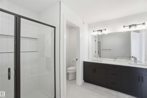 Bathroom featuring double vanity, a shower stall, and light tile patterned flooring - 6949 176A Avenue, Edmonton, AB - Indoor Photo Showing Bathroom