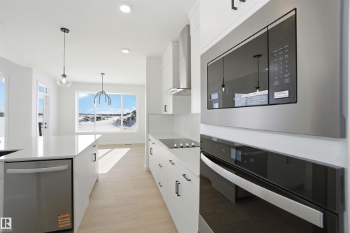 Kitchen featuring stainless steel appliances, white cabinetry, light wood-style flooring, modern cabinets, and pendant lighting - 6949 176A Avenue, Edmonton, AB - Indoor Photo Showing Kitchen With Upgraded Kitchen