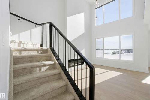 Stairs featuring a high ceiling, wood finished floors, and a water view - 6949 176A Avenue, Edmonton, AB - Indoor Photo Showing Other Room