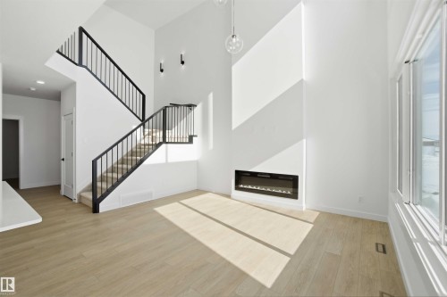 Entrance foyer with light wood-type flooring, a glass covered fireplace, and a high ceiling - 6949 176A Avenue, Edmonton, AB - Indoor With Fireplace