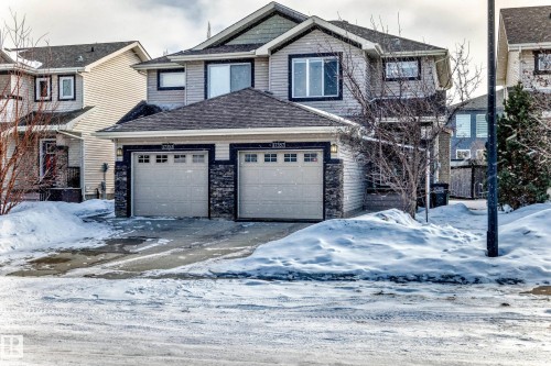 Craftsman-style home featuring an attached garage, a shingled roof, driveway, and stone siding - 17357 8A Avenue, Edmonton, AB 