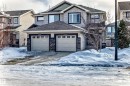 Craftsman-style home featuring an attached garage, a shingled roof, driveway, and stone siding - 17357 8A Avenue, Edmonton, AB 