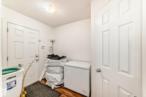 Laundry area with a textured ceiling and dark wood-style floors - 17357 8A Avenue, Edmonton, AB 