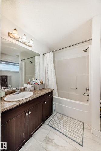 Bathroom with vanity, shower / bath combo, and light marble finish flooring - 17357 8A Avenue, Edmonton, AB 