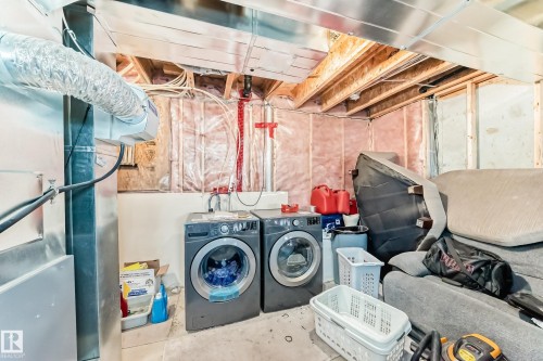 Laundry area featuring concrete floors, washer and dryer, and heating unit - 17357 8A Avenue, Edmonton, AB 