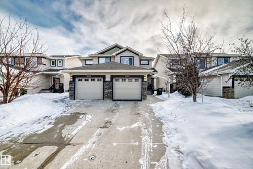 View of front of home featuring a garage, stone siding, concrete driveway, and a shingled roof - 17357 8A Avenue, Edmonton, AB 