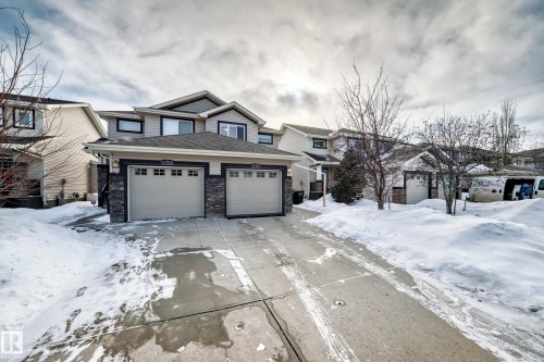 View of front of home featuring stone siding, a garage, concrete driveway, and roof with shingles - 17357 8A Avenue, Edmonton, AB 