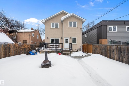 Snow covered back of property featuring a fenced backyard, a deck, and stucco siding - 10623 75 Avenue, Edmonton, AB - Outdoor